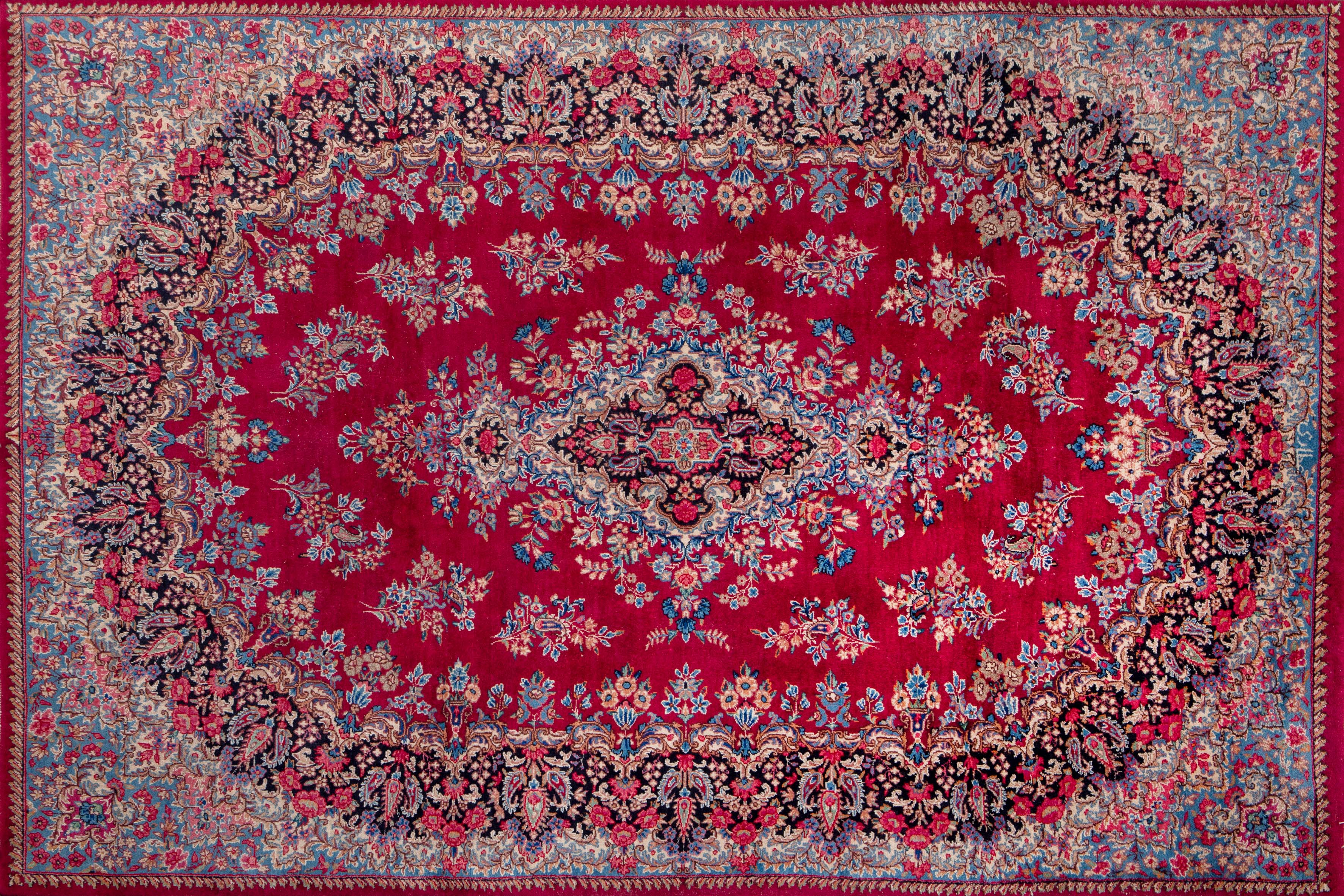 Alfombra persa  de lana en granate con campo de flores, firmada.
Medidas: 300 x 200 cm.