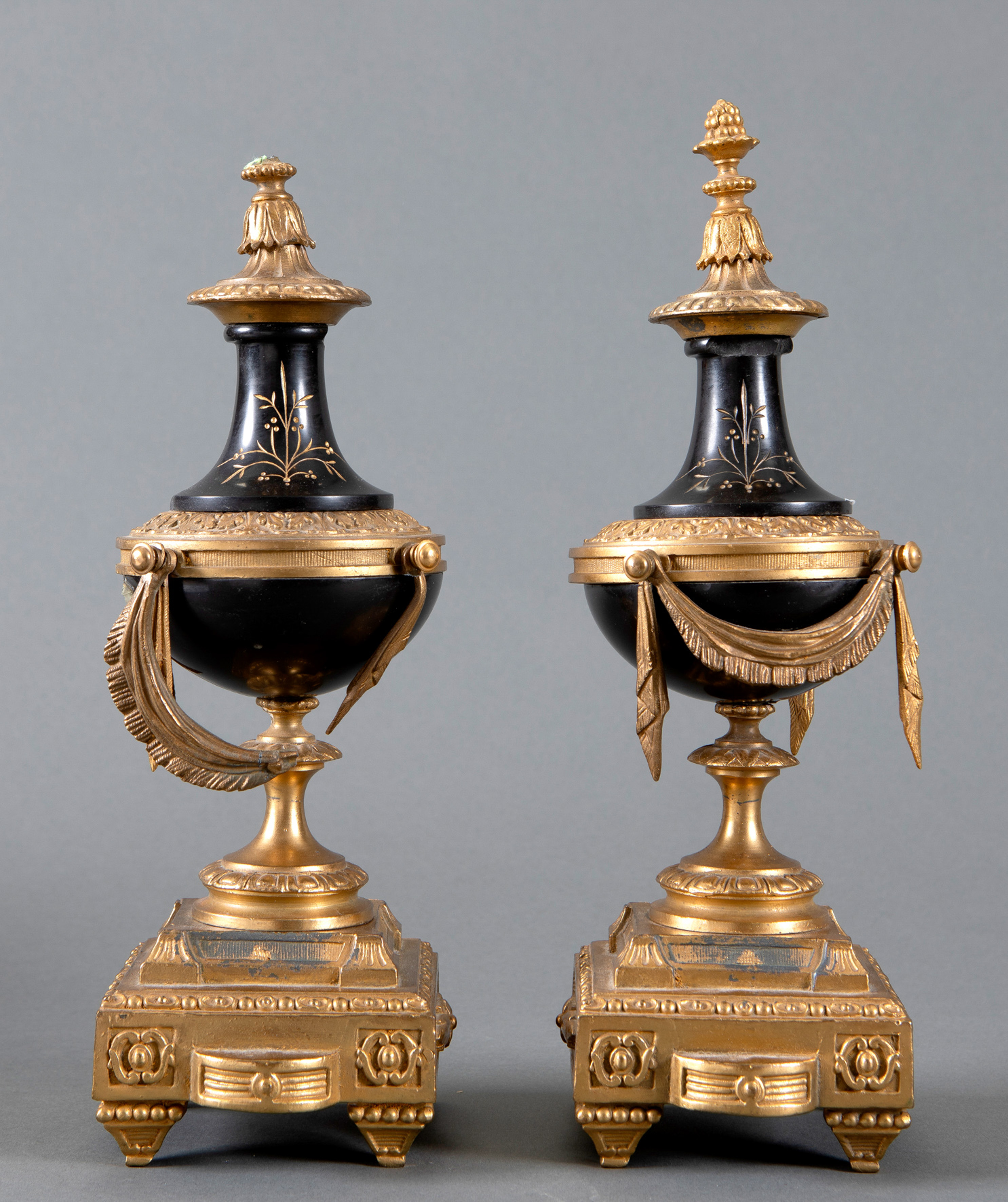 Pareja de pequeñas copas estilizadas en bronce dorado con remates de piñas, colgaduras y motivos...