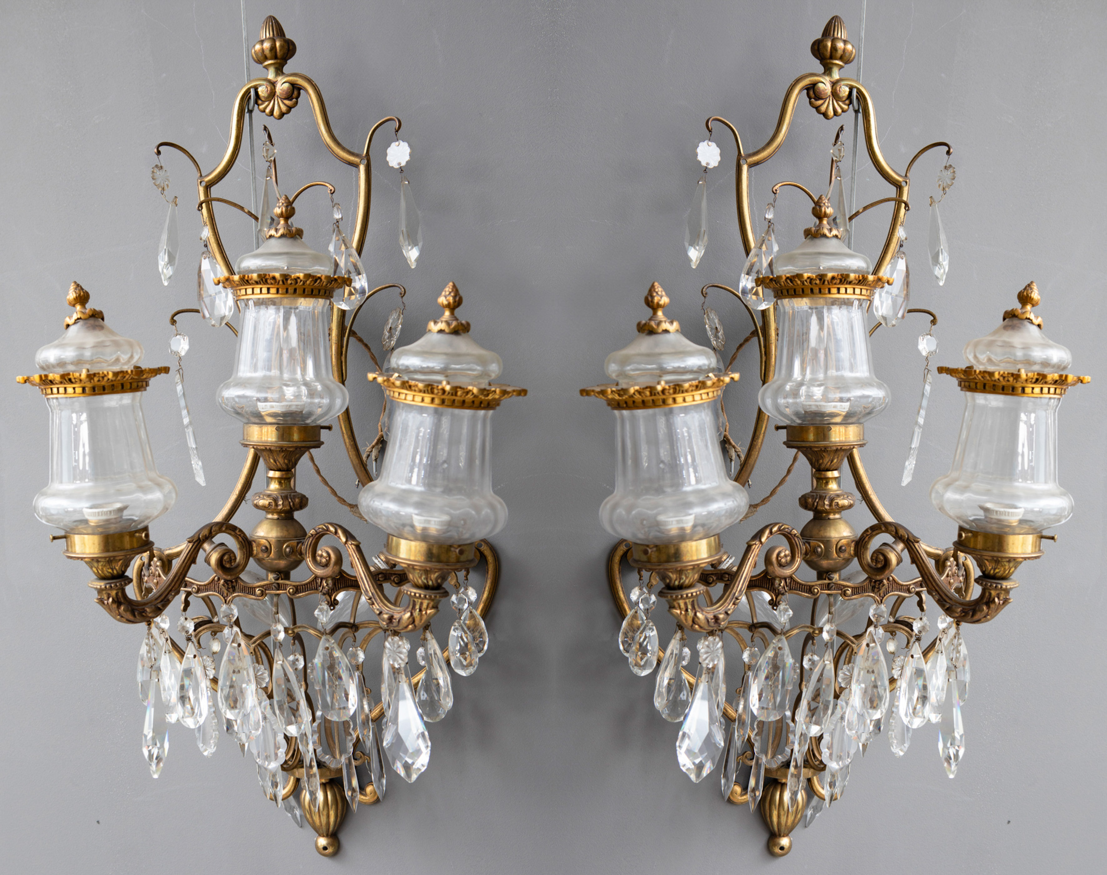 Pareja de apliques de tres luces en bronce dorado con decoración de cuentas en cristal y prismas...