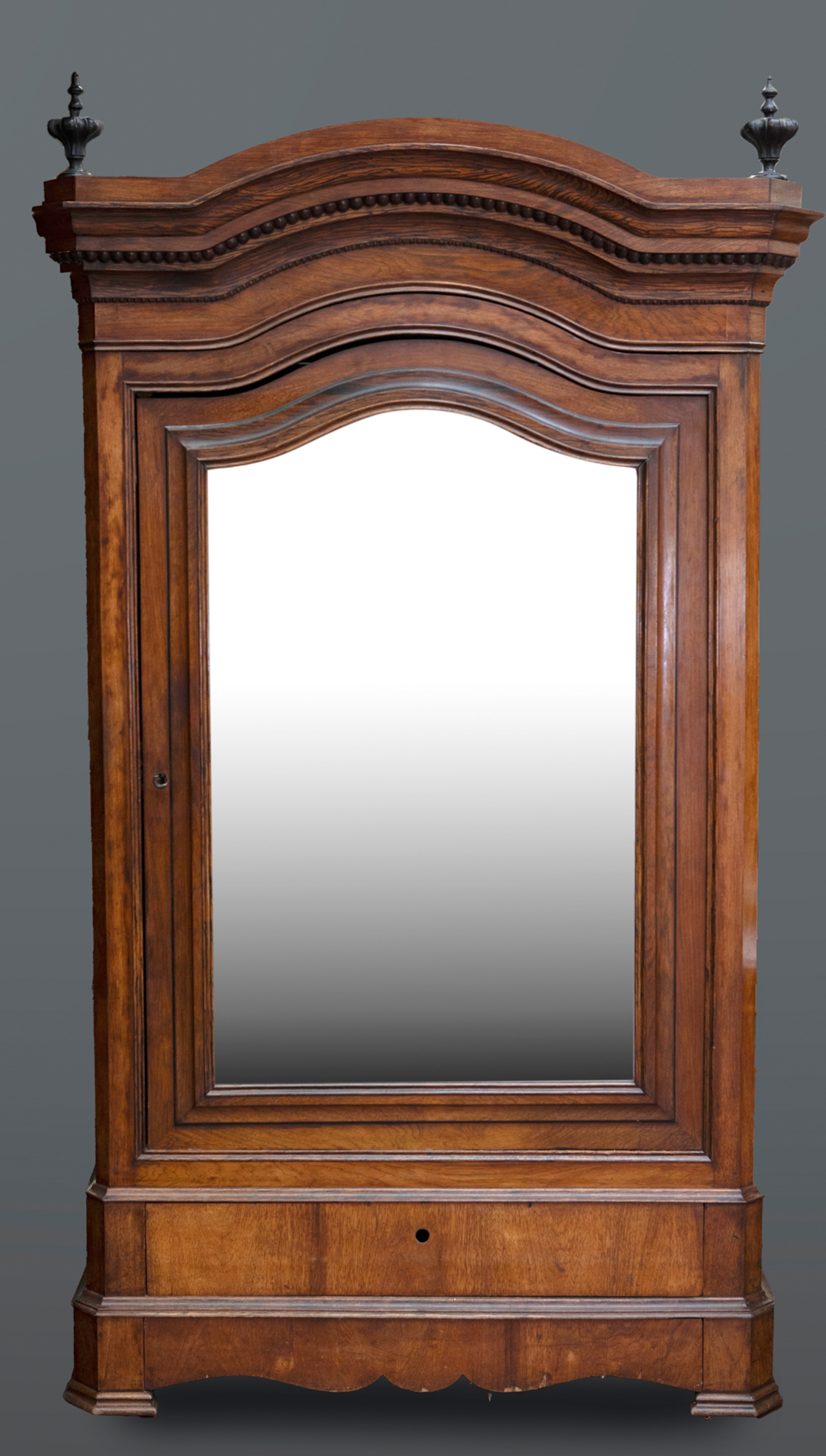 Armario de estilo alfonsino en madera de nogal con copete partido y remates de trofeos. Puerta con...