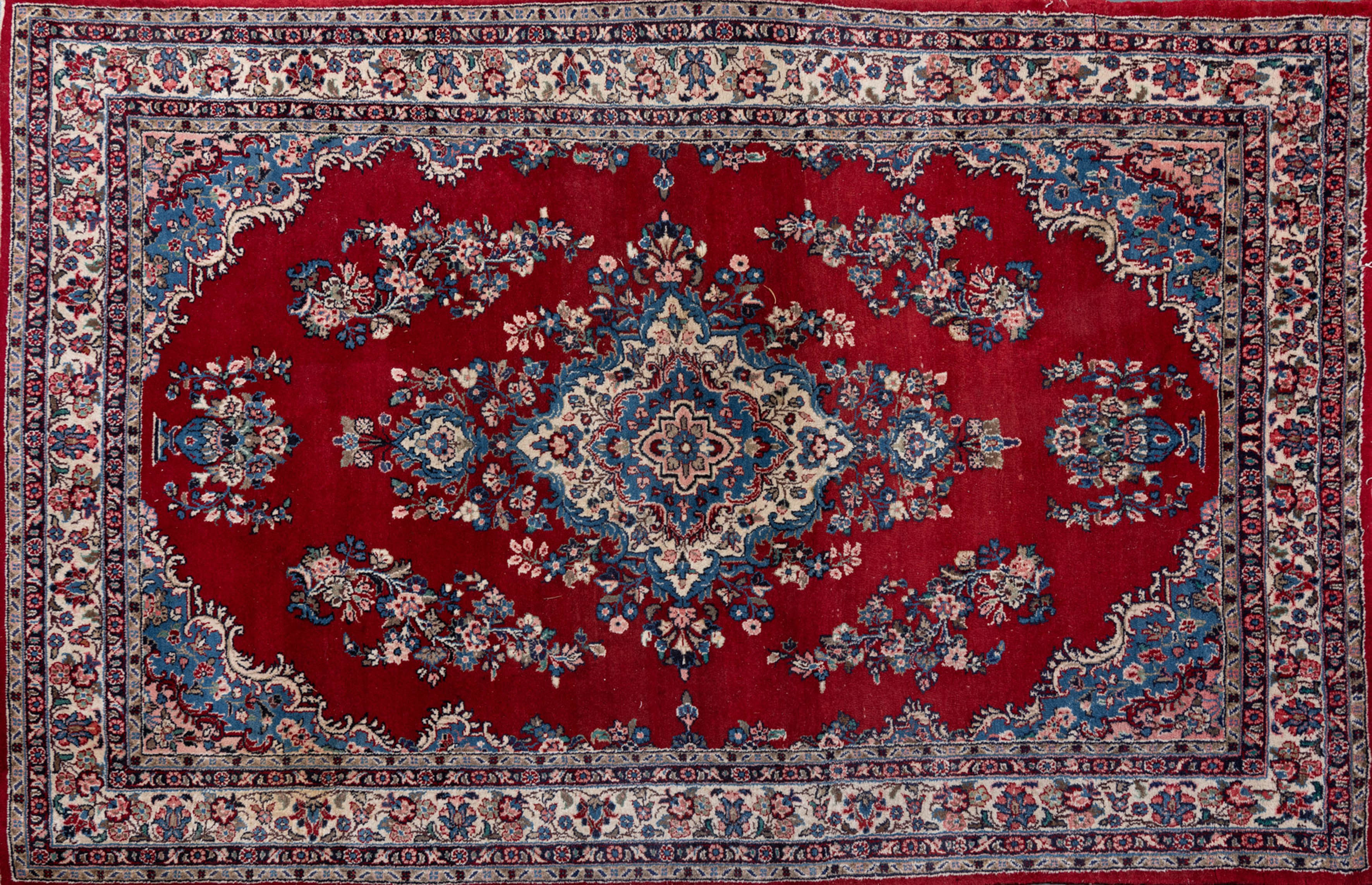 Alfombra persa en campo color rojo con medallón central y decoración de jarrones  flores. Bordura...