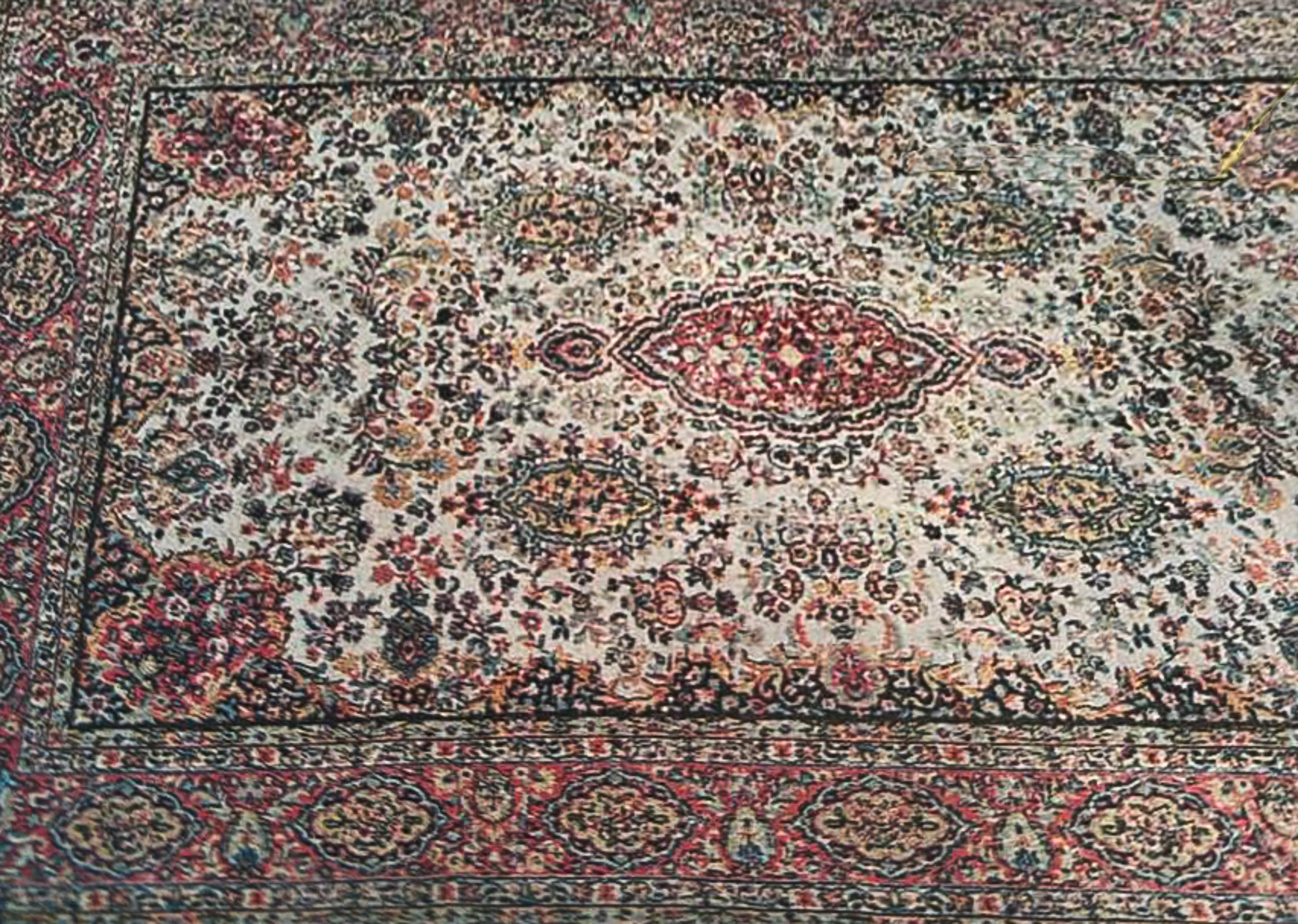 Alfombra oriental sobre campo color crudo con decoración de jarrones, flores y medallones. Bordura...