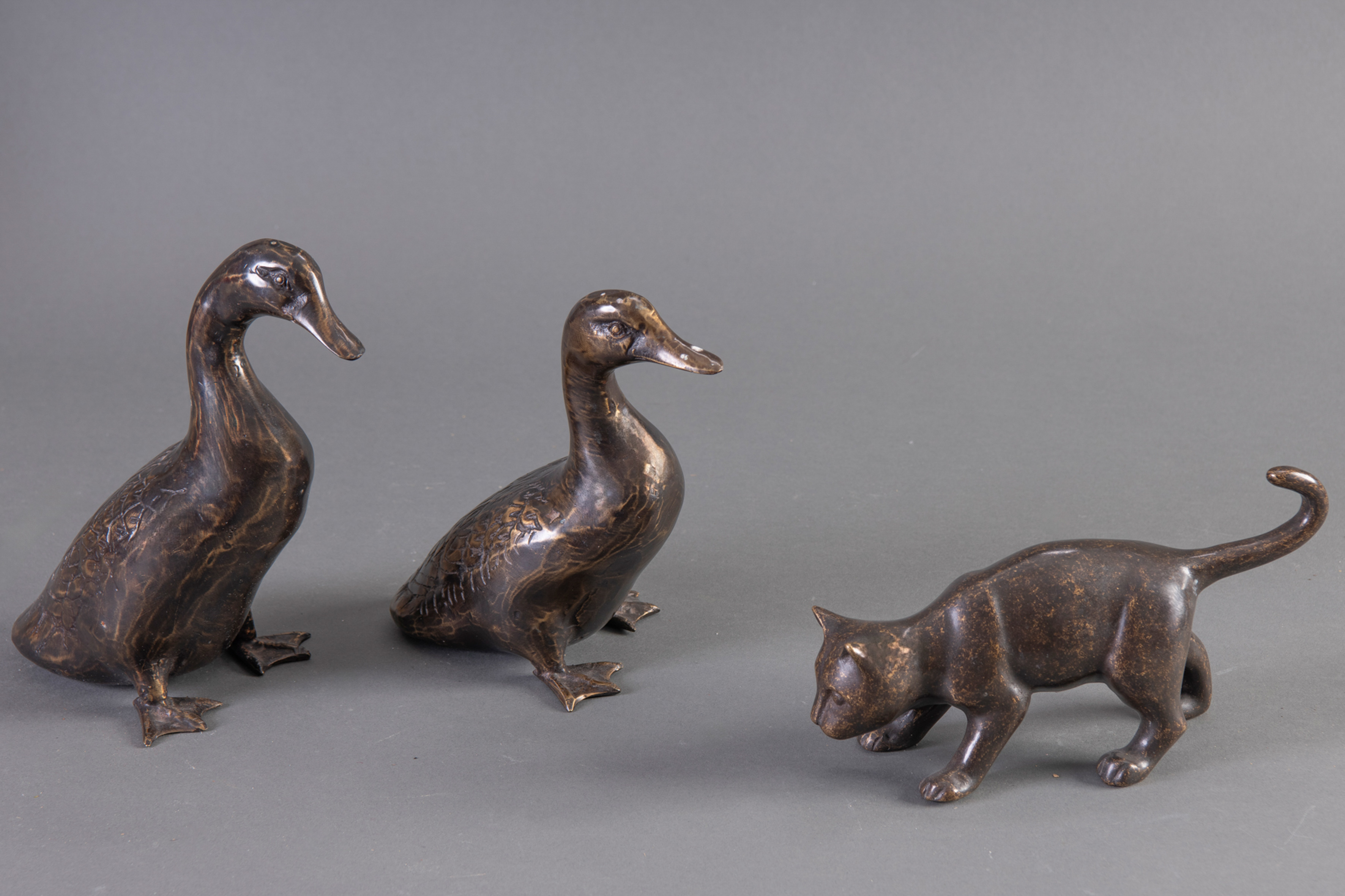 Conjunto contemporaneo en bronce pavonado, compuesto por dos patos y un gato.