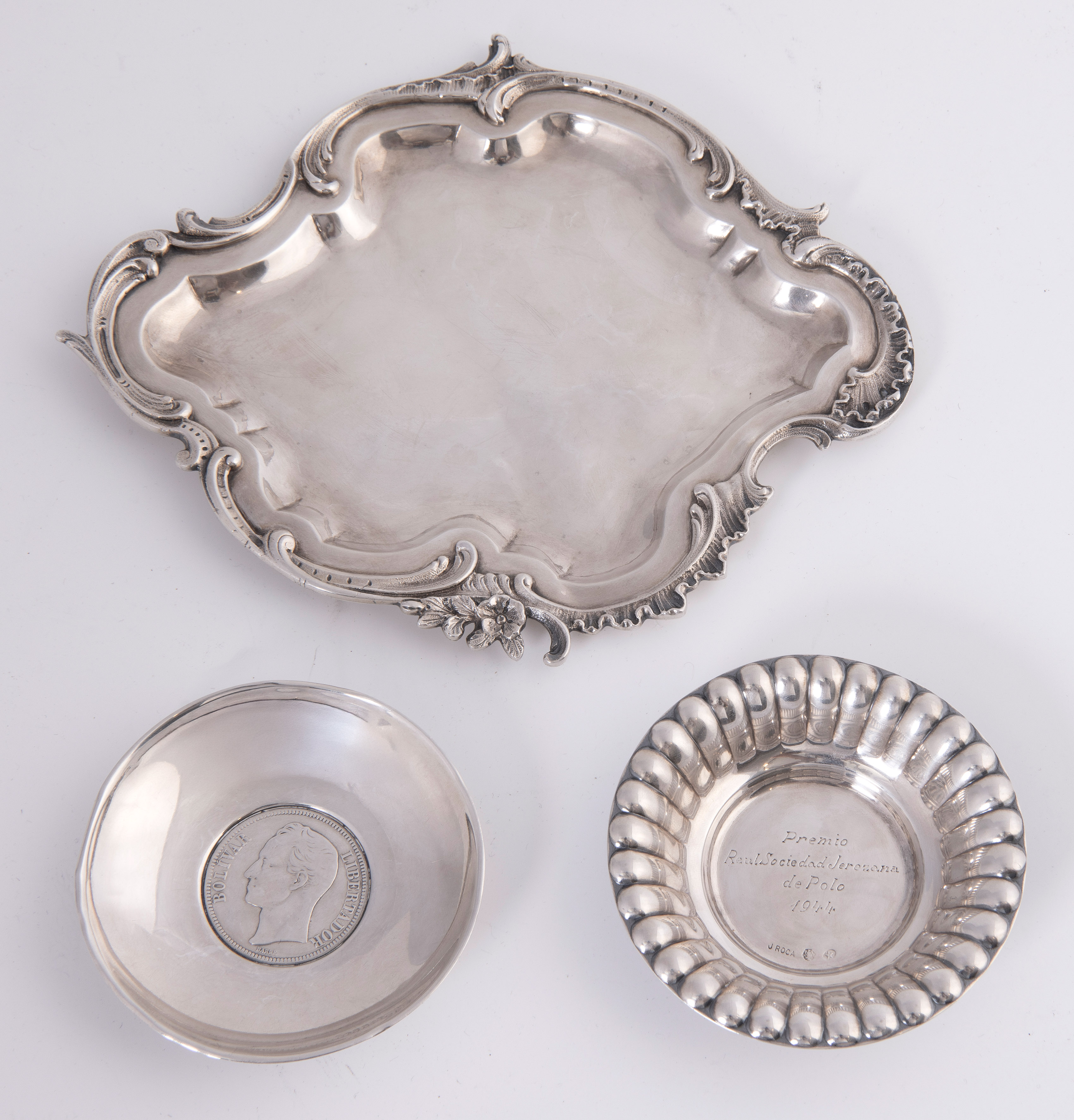 Lote en plata española punzonada formado por: bandejita de estilo Rococó, otra pequeña circular con...