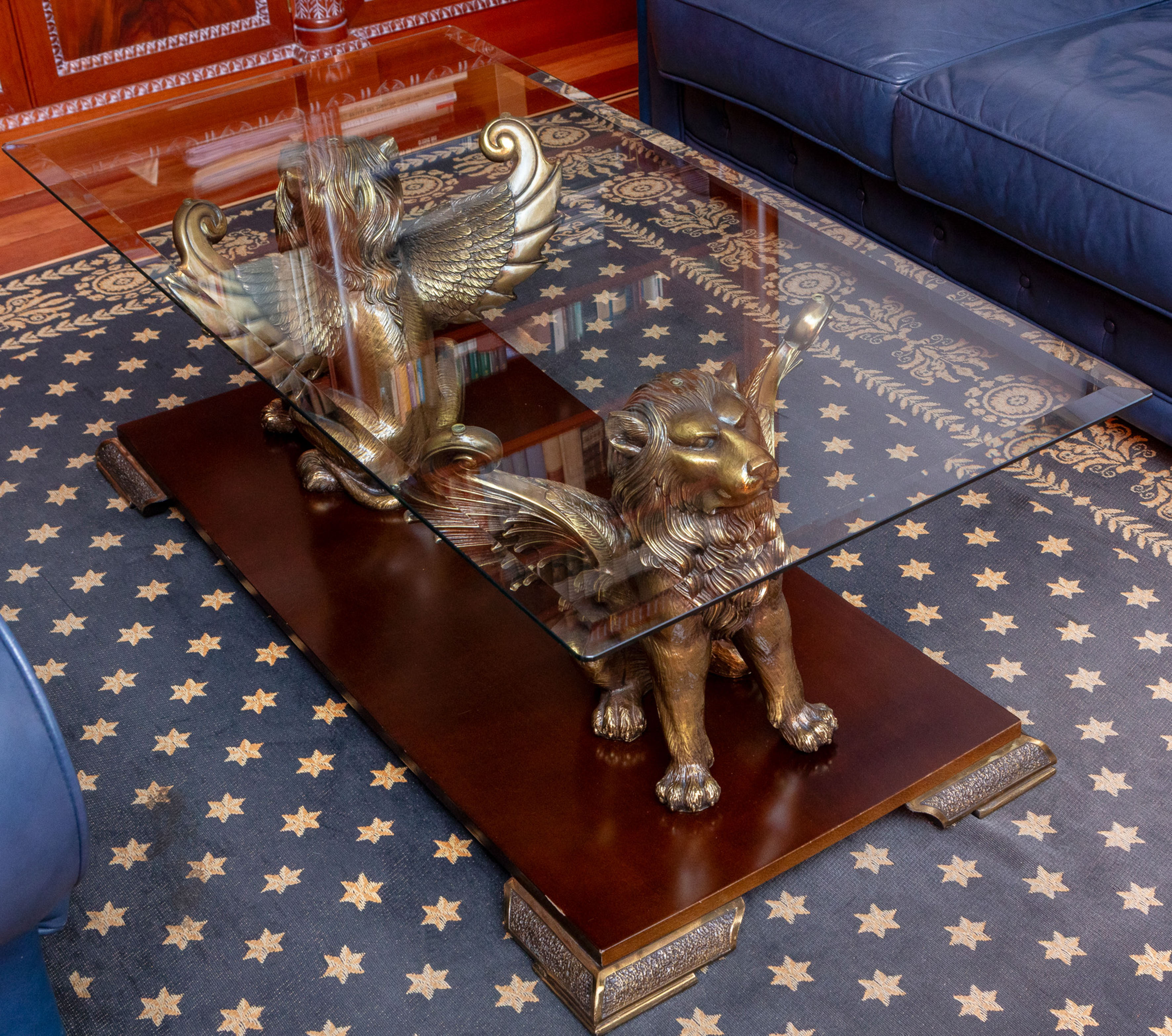 Mesa de diseño contemporáneo con tapa de cristal biselado que apoya sobre dos leones alados en...