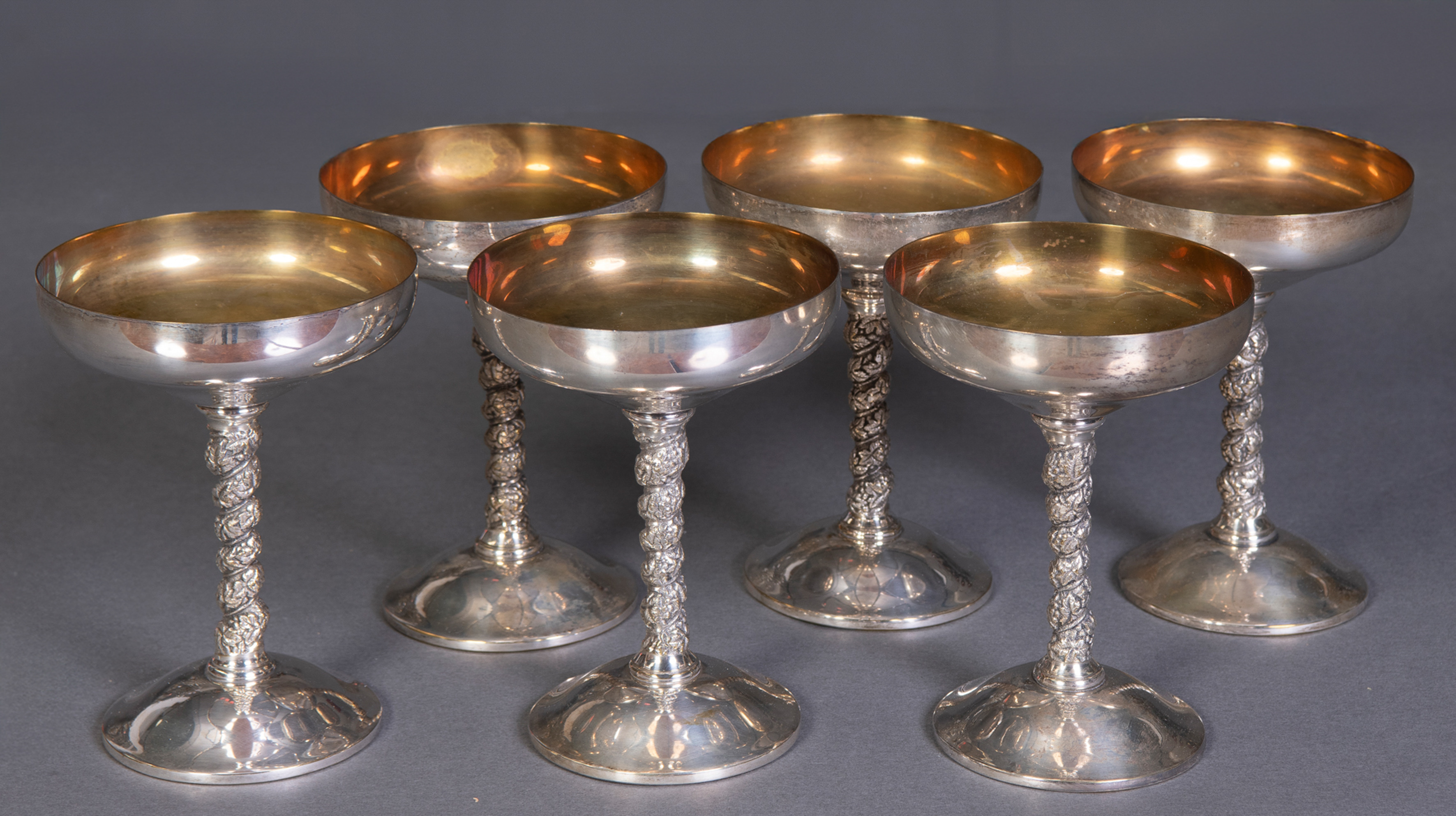 Lote de mesa en metal plateado compuesto por:
Seis copas de champán en plateado con fuste...
