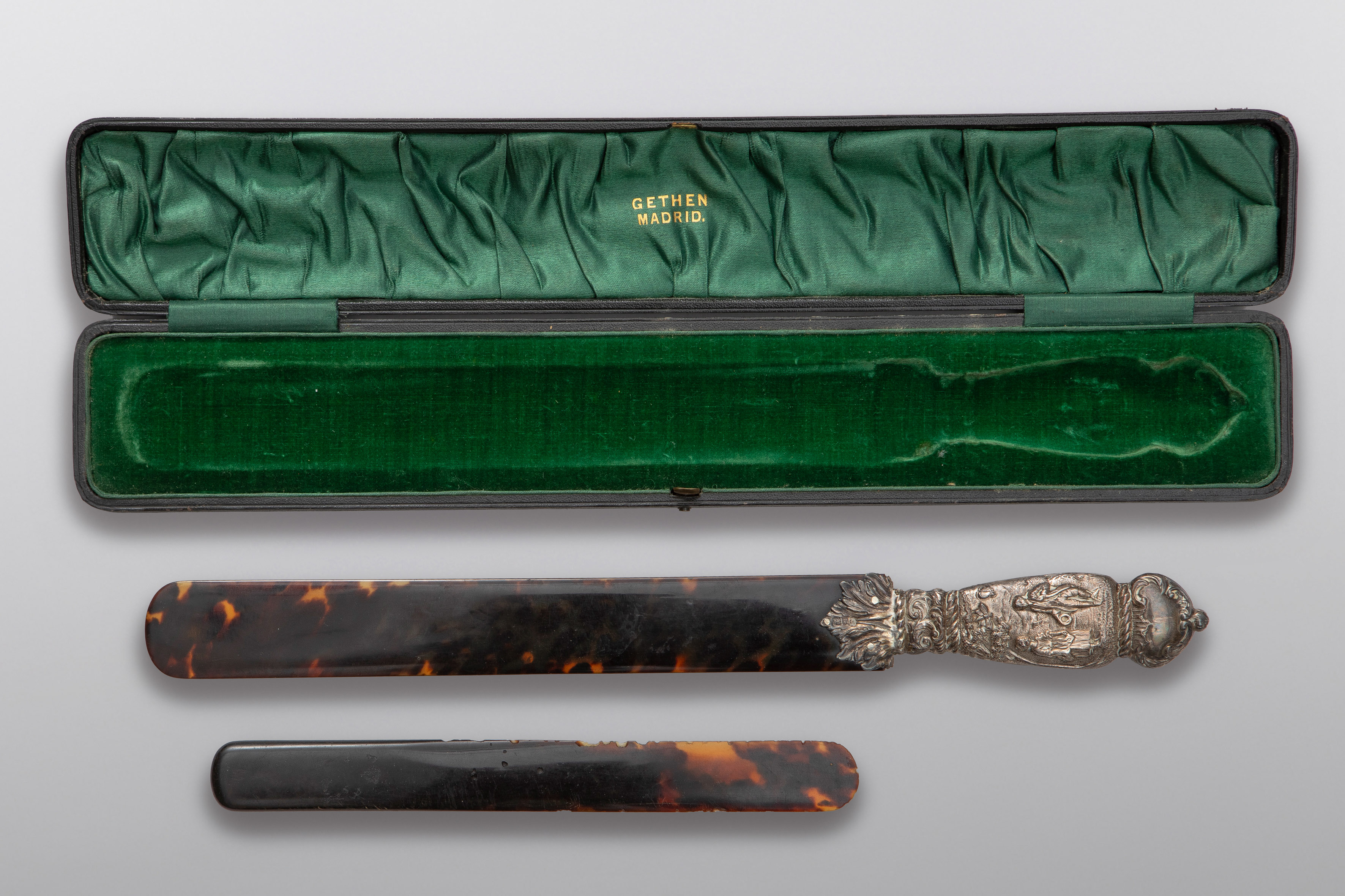 Lote formado por un plegador antiguo con empuñadura de plata y un calzador en carey. Con estuche....