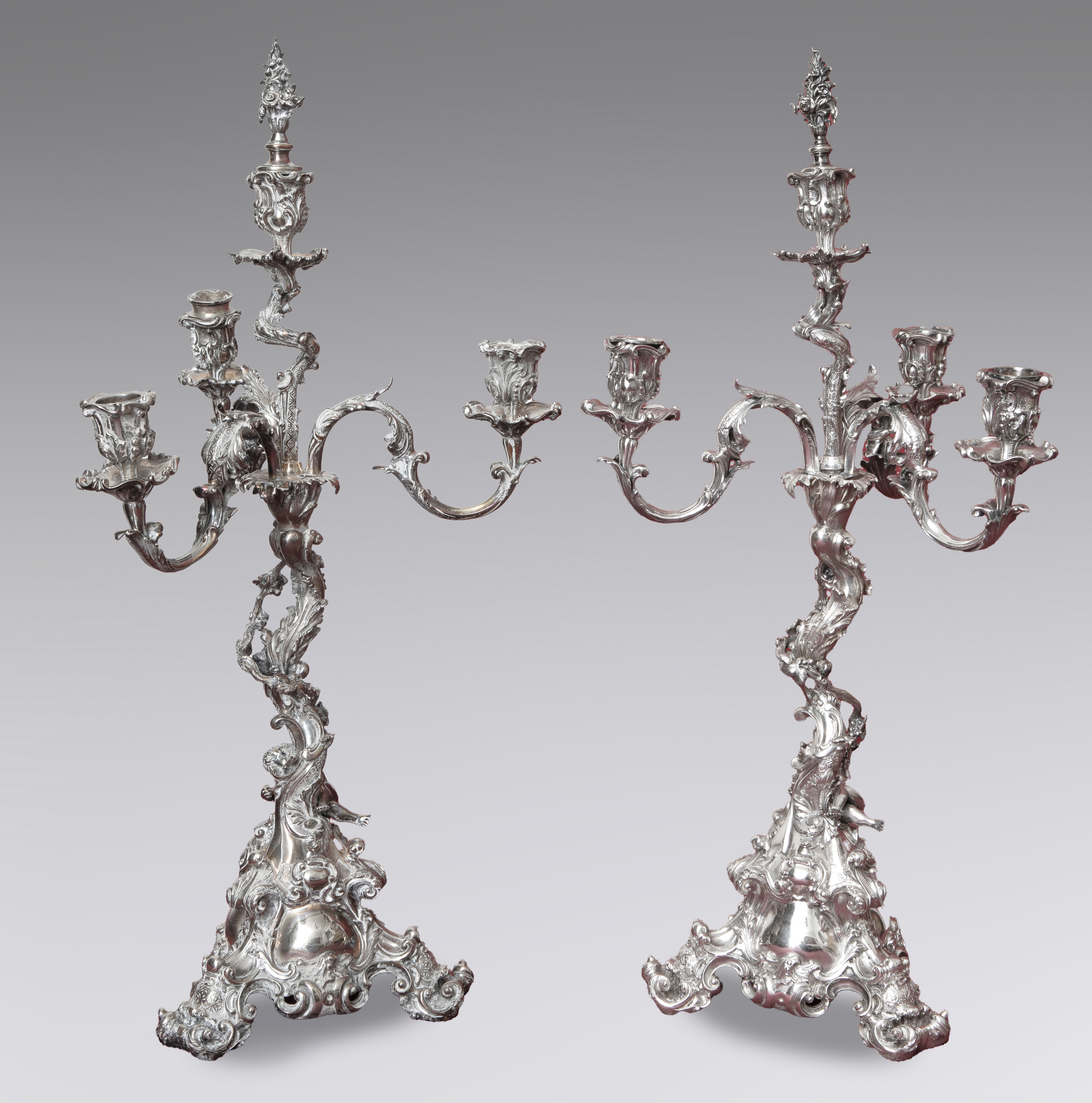 Candelabros antiguos en metal plateado. Elegante fuste de querubines entrelazados en el tronco con...