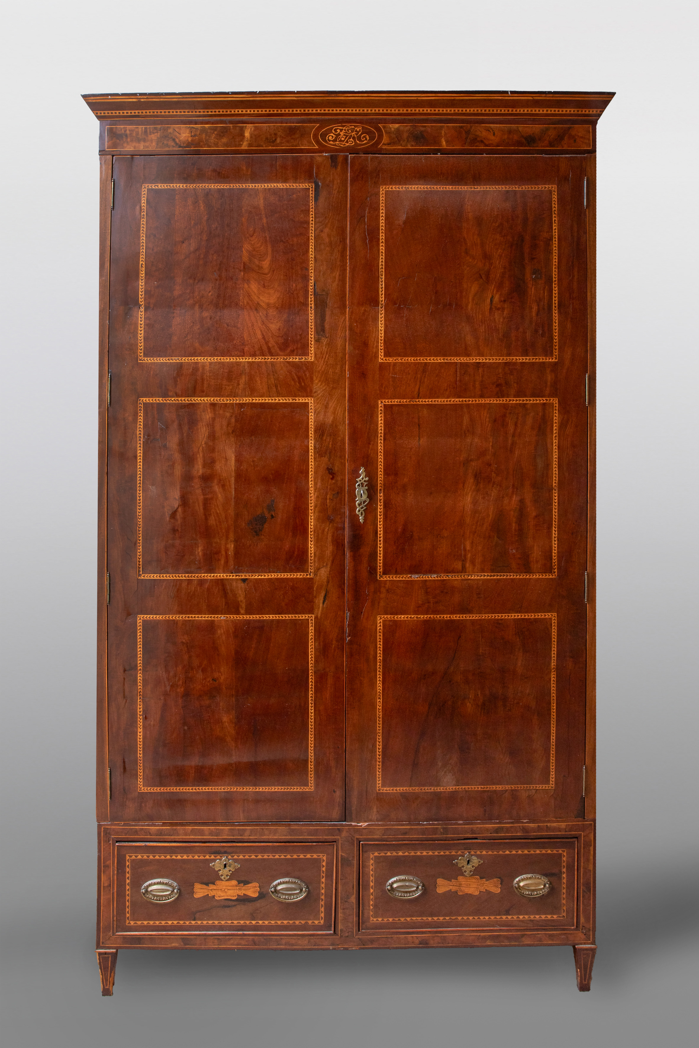 Armario alto en madera de pino con marquetería.
Frente con dos puertas con decoración de fileteado...