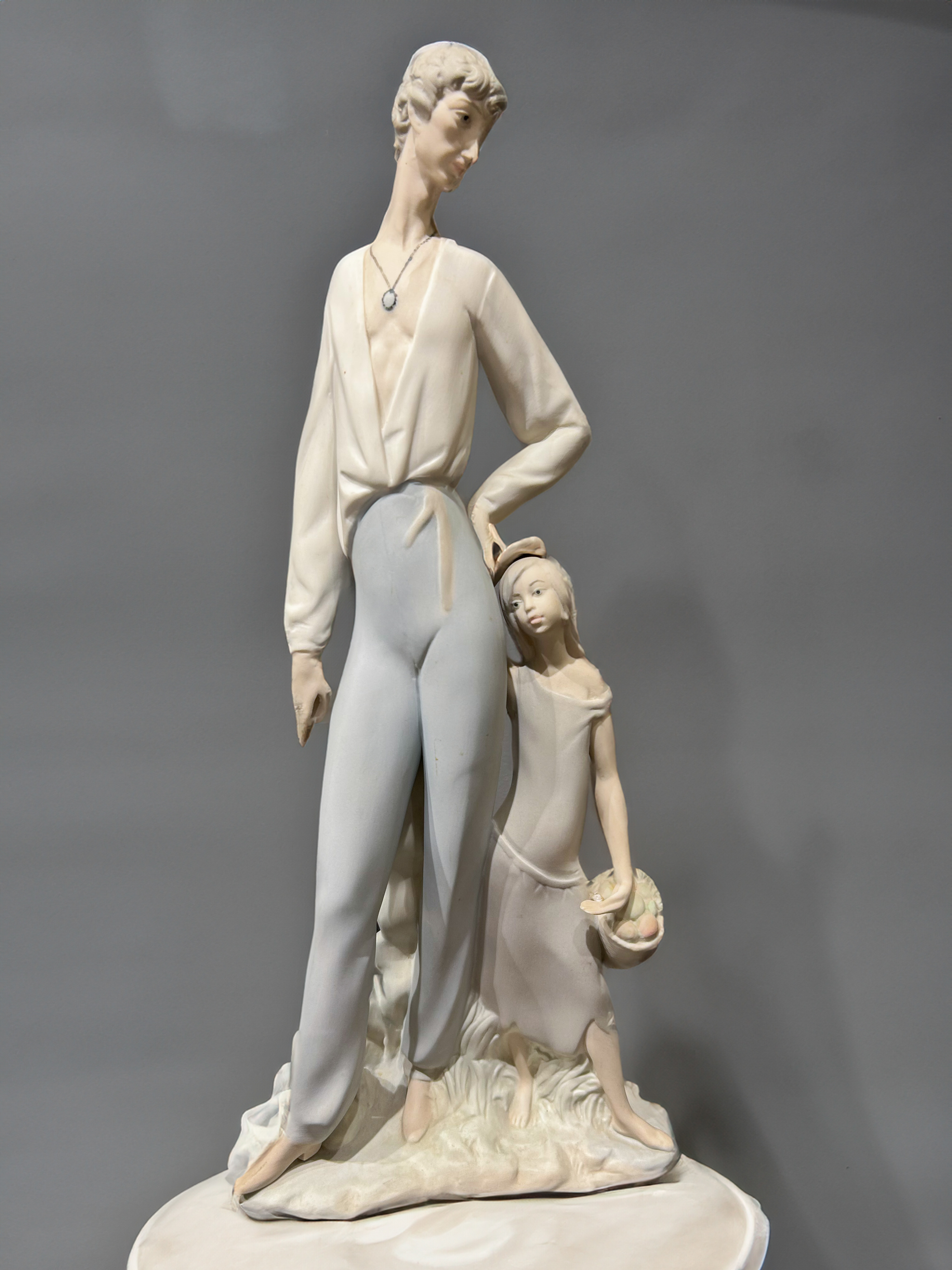 Figura en biscuit con un padre y una hija que sujeta un cesto de manzanas, España, S. XX
Altura: 39...