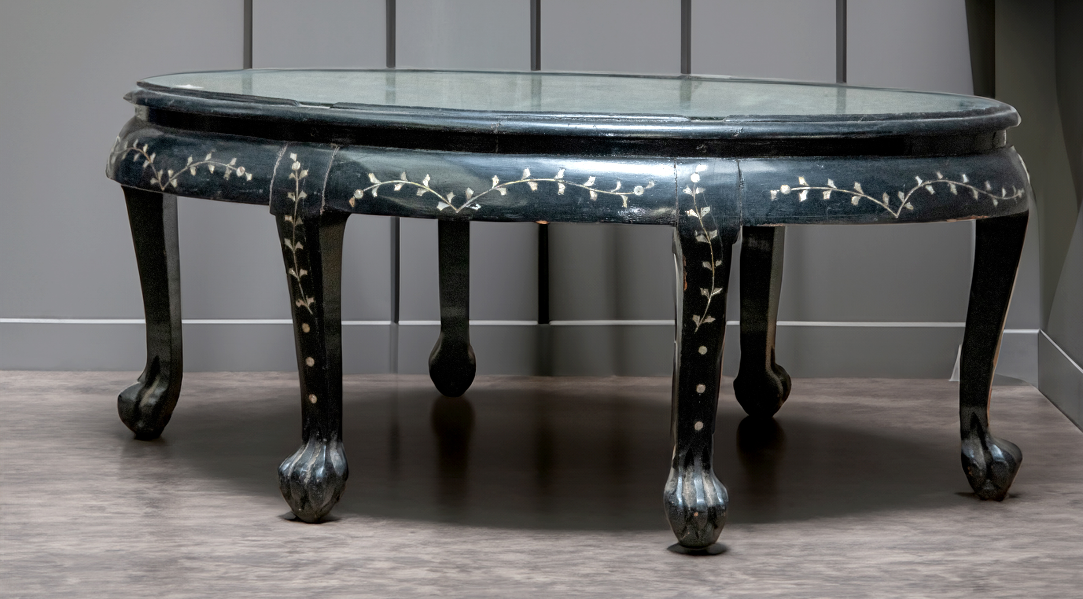 Mesa baja de centro oriental en madera ebonizada y nácar sobre patas de garra y bola. Paisaje...