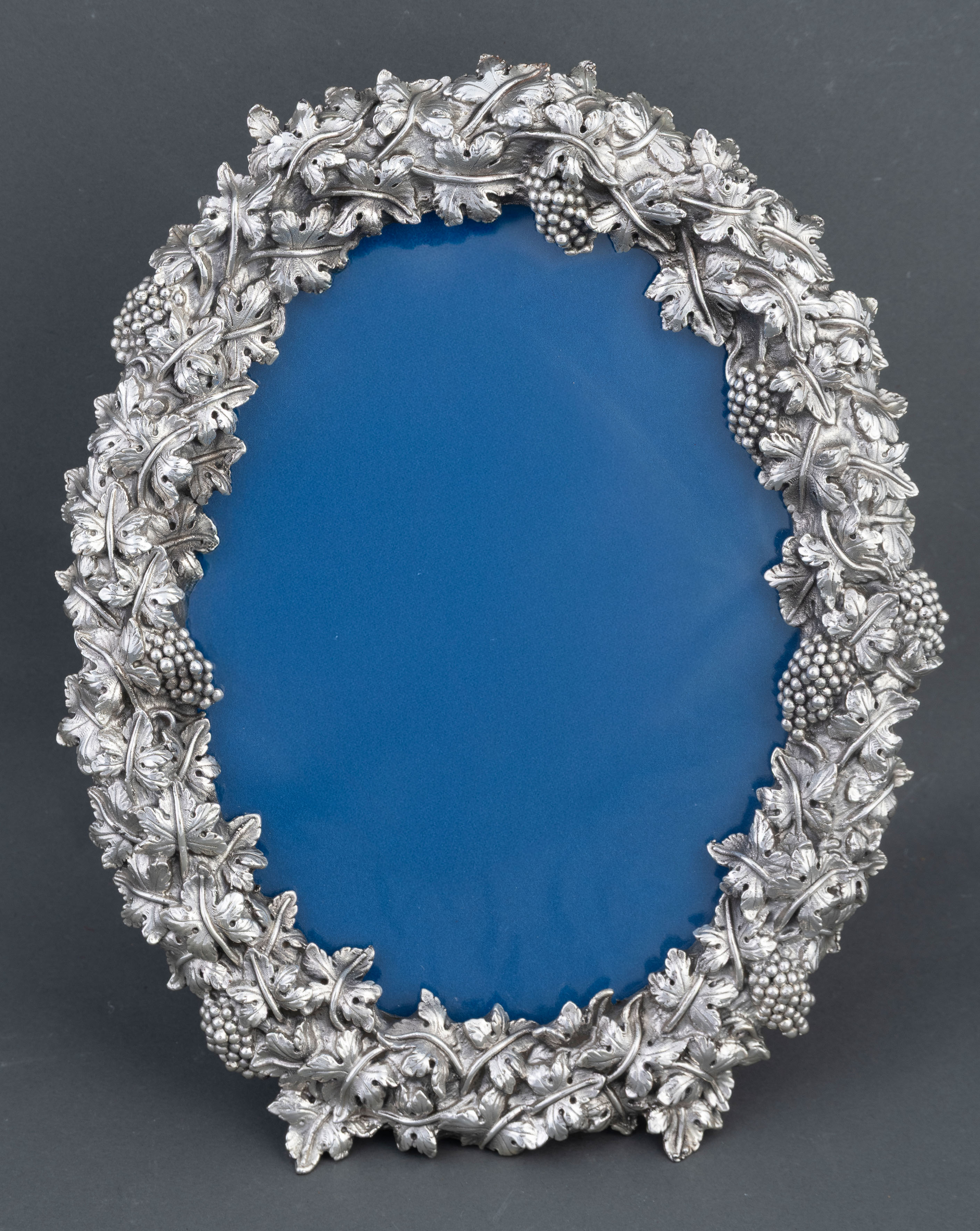Marco oval en plata con profusa decoración repujada de flores y frutos. 
Medidas: 28 x 21 cm.
En su...
