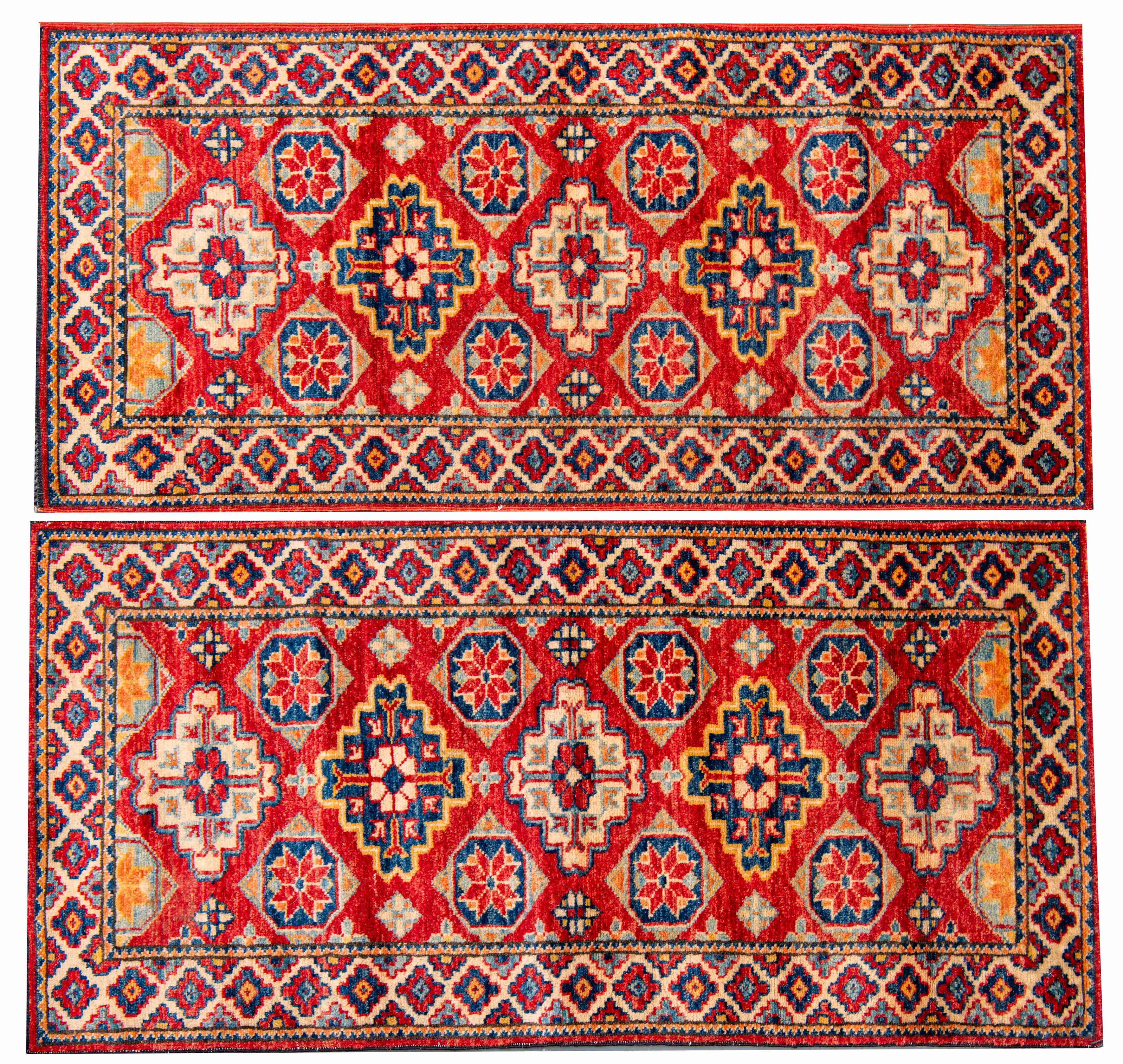 Pareja de alfombras de pasillo con campo color rojo y decoración de motivos romboidales...