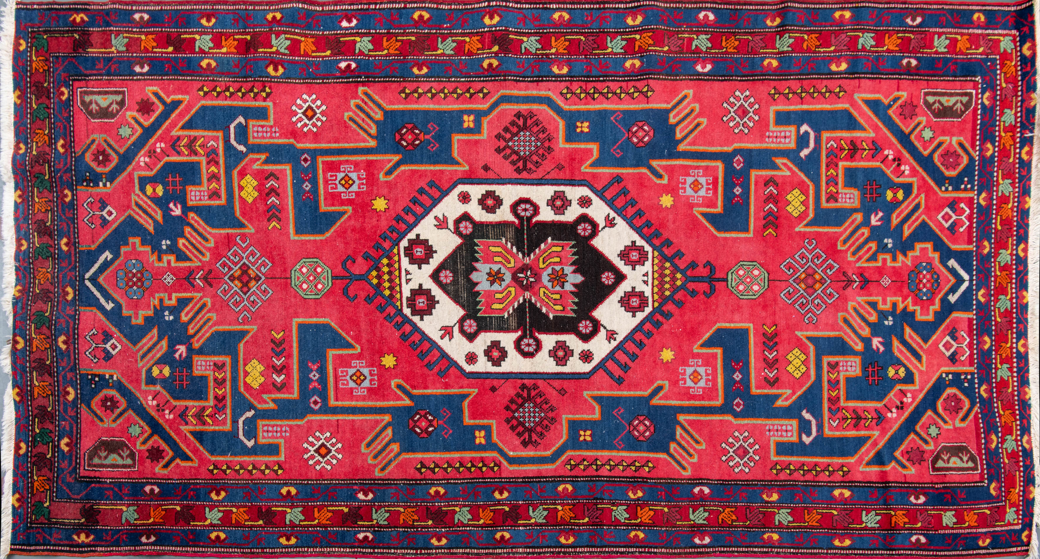 Alfombra persa. Campo en color coral y medallón central con fondo blanco.
Medidas: 218 x 121 cm.