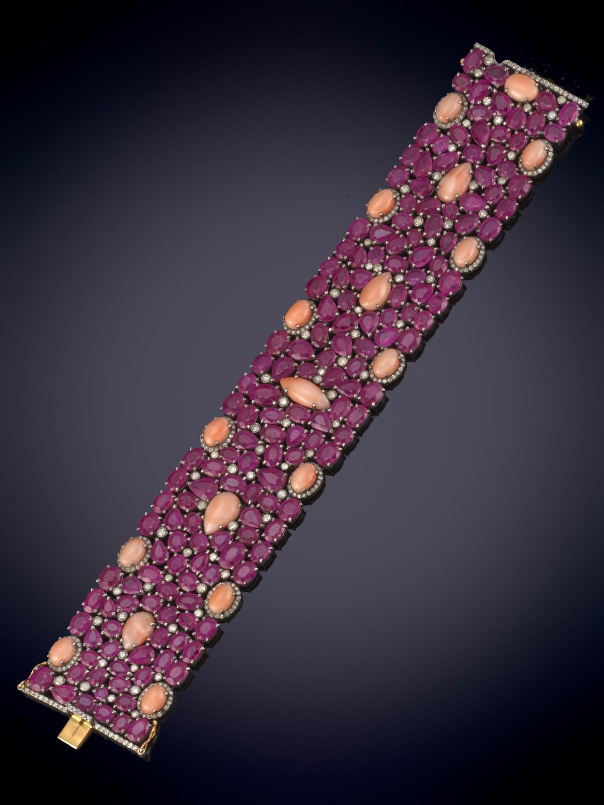 BRAZALETE FLEXIBLE DE RUBÍES CON UN PESO DE 121.80 CTS.SALPICADO DE CORALES EN TALLA CABUJÓN OVAL,...