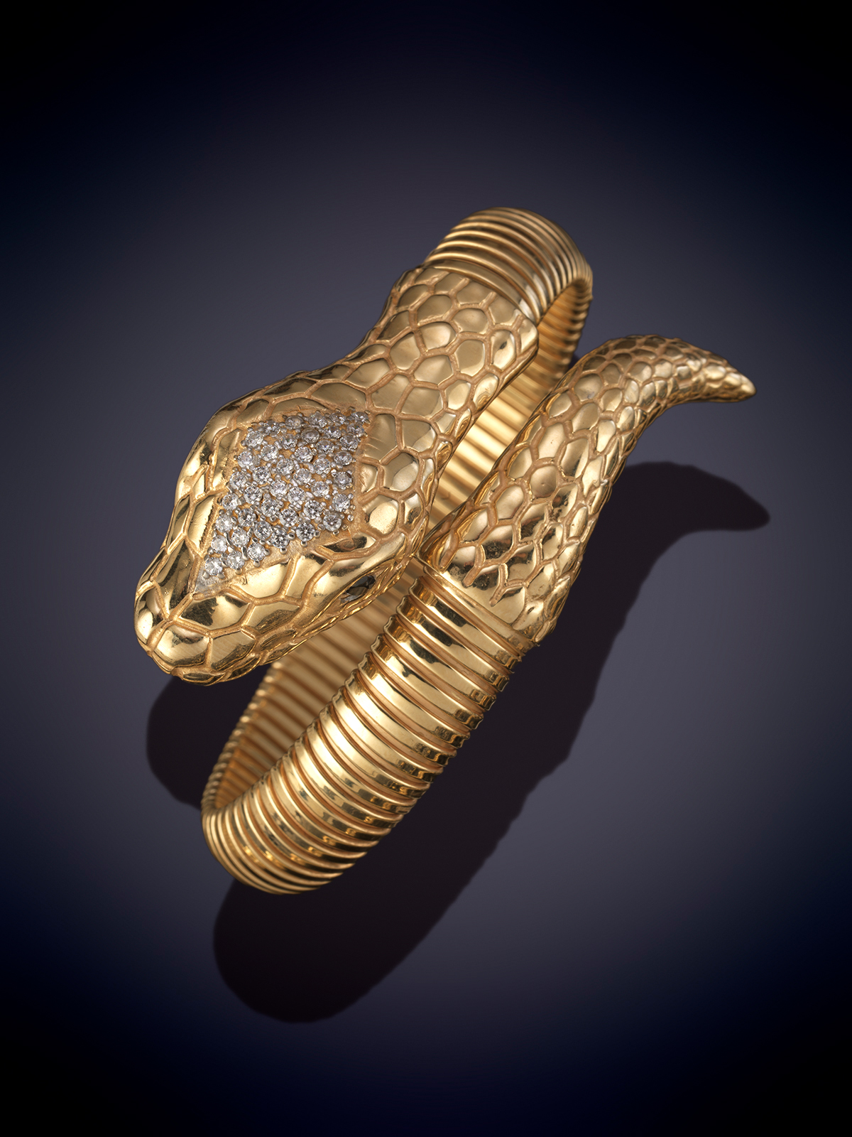 BRAZALETE TUBOGAS CON CABEZA Y COLA DE SERPIENTE. Montura en plata con baño de oro amarillo de 18k.