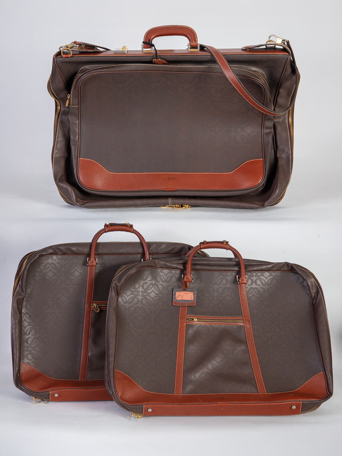LOEWE.
Lote de dos bolsas de viaje y un portatrajes en piel.