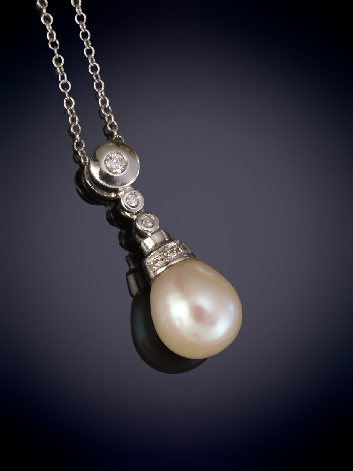 COLGANTE CON PERLA DE BELLO ORIENTE Y CASQUILLA CON BRILLANTES, CON CADENA DE ORO BLANCO DE 18K.
