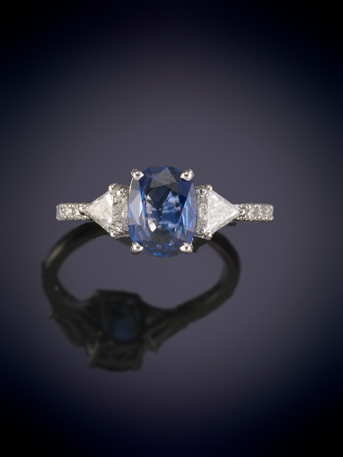 ANILLO CON UNA  TANZANITA OVAL  FLANQUEADA POR DOS DIAMANTES TALLA TRIANGULO Y BRAZOS CON...