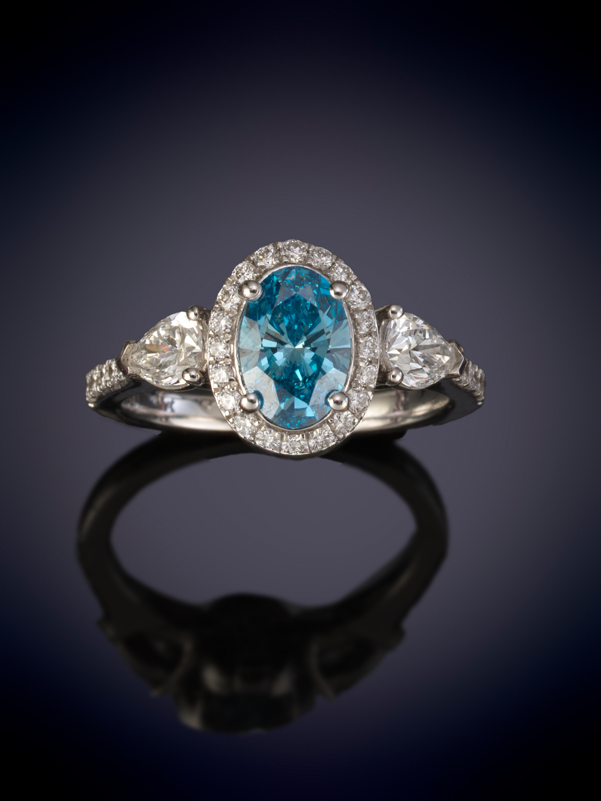 SORTIJA CON UN DIAMANTE AZUL TALLA OVAL CON UN PESO DE 1 CT. DE LABORATORIO. ORLADA DE BRILLANTES...