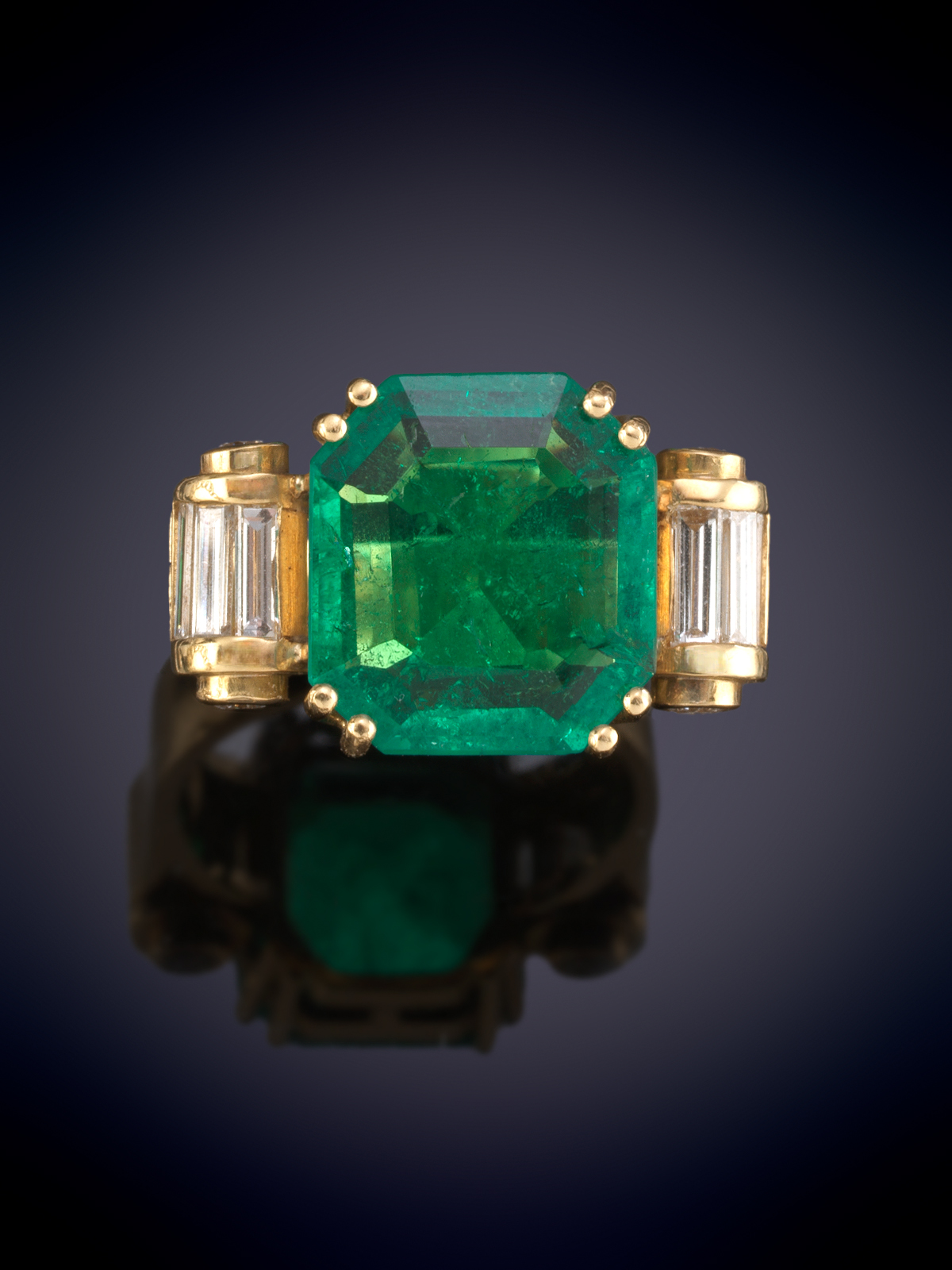 SORTIJA CON ESMERALDA COLOMBIANA DE BELLO COLOR FLANQUEADA POR BAGUETTES. ORIGINAL MONTURA EN ORO AMARILLO DE 18K. Peso esmeralda 4ct aprox. 